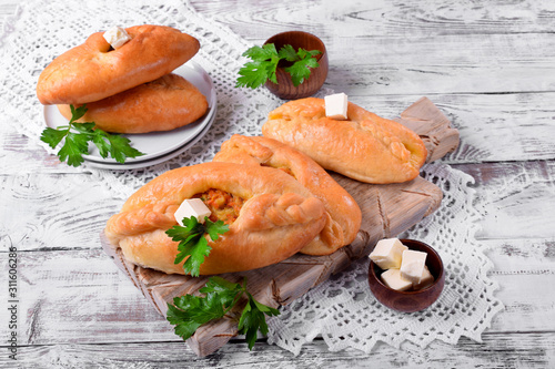 Rasstegai pie of yeast dough with meat filling on white wooden table. Traditional meal of Russian cuisine photo