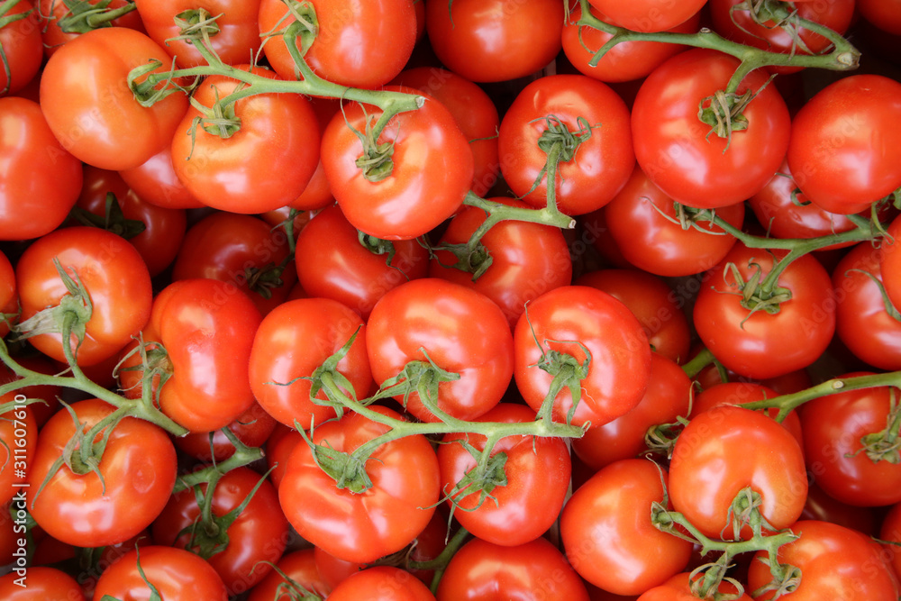 Pile of tomatoes for sale at supermarket. Background image on the subject of organic, vegan or vegetarian raw food.