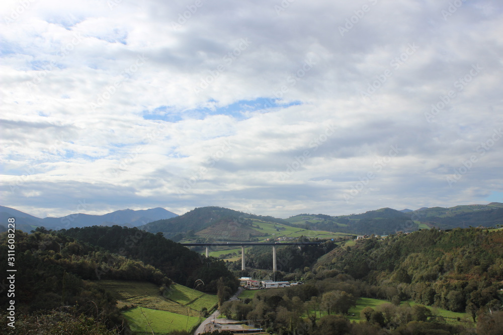 Fototapeta premium Green landscape with bridge and cloudy sky