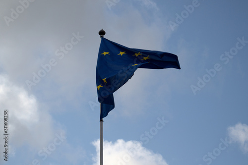 the blue flag of the European Union flutters in the wind against the blue sky, copy space 