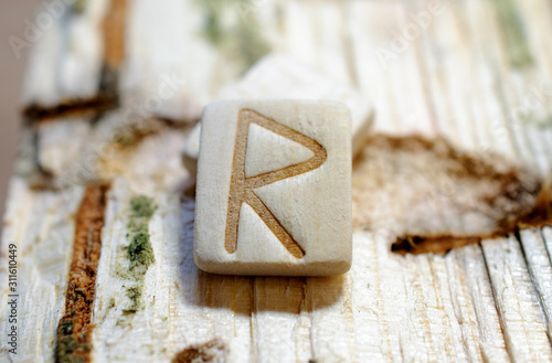 Wooden rune Raido close-up on a wooden background. Soft focus photo