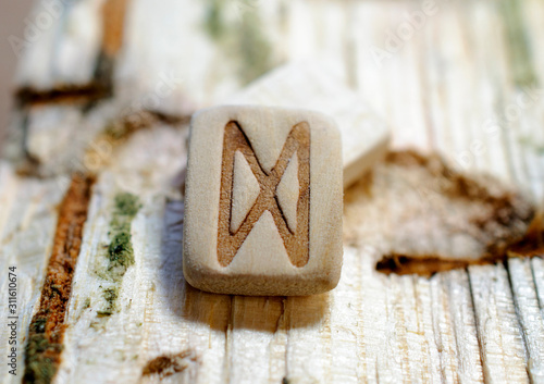 Wooden rune Dagaz close-up on a wooden background. Soft focus photo