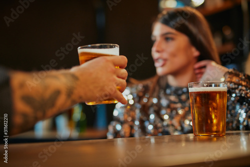Foto Close up of couple sitting next to bar counter, drinking beer and flirting