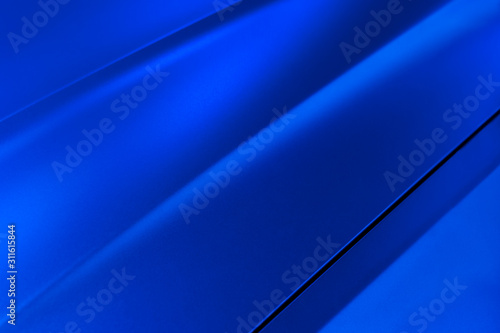 Surface of blue sport sedan car metal hood, part of vehicle bodywork, steel gradient line pattern, selective focus