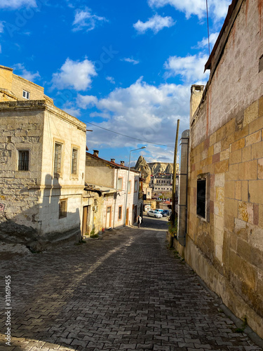 Deserted street of the old turkish city. Ancient brick houses with arches and windows on a background of mountains. Cappadocia