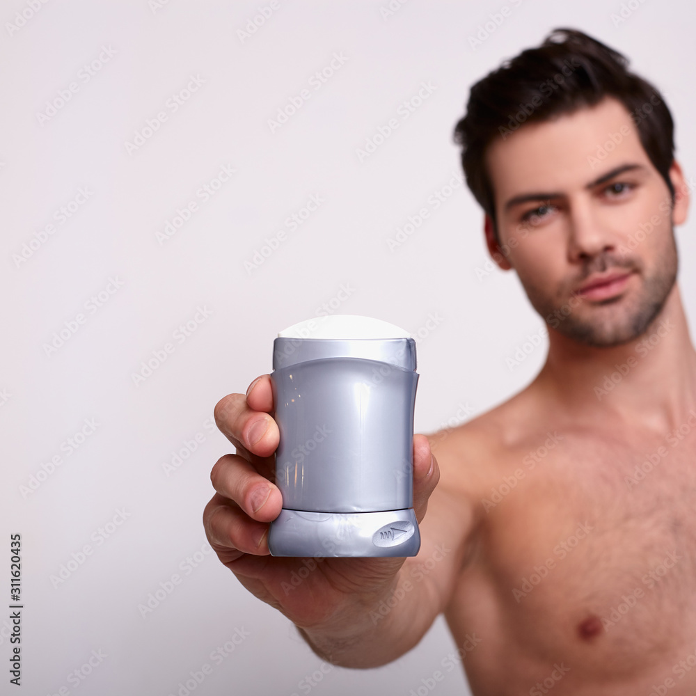 Strong sexy man holds deodorant at white background Strong sexy man holds deodorant at white background