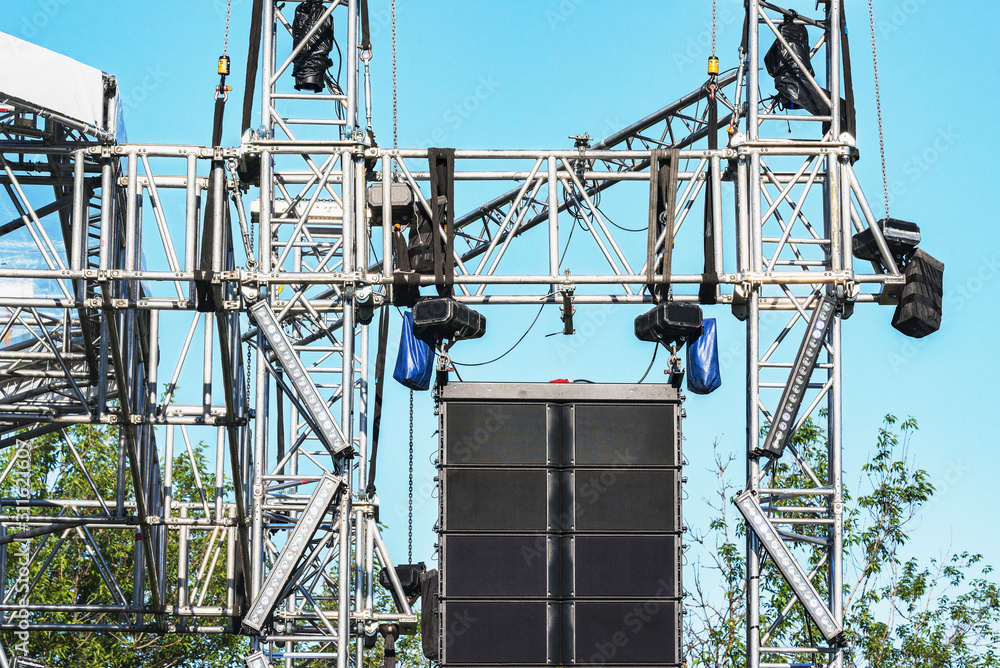 Sound system by the stage at concert time. Open air event equipment. Summer outdoor music festival preparation.