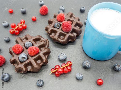 delicious waffles with forest berries and jar of milk breakfast concept