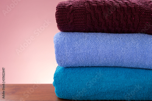 Stack of clean clothes over colored background with copy space. Close up and selective focus. Household concept