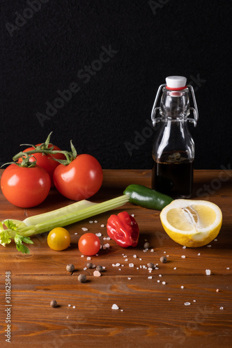 Fresh organic tomato juice decorated with raw tomatoes, leaves on a dark rustic wooden background. Healthy diet nutrition concept. 