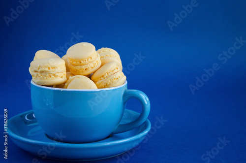 On a blue classic background, a blue cup with macaron horizontal view, soft focus, closeup