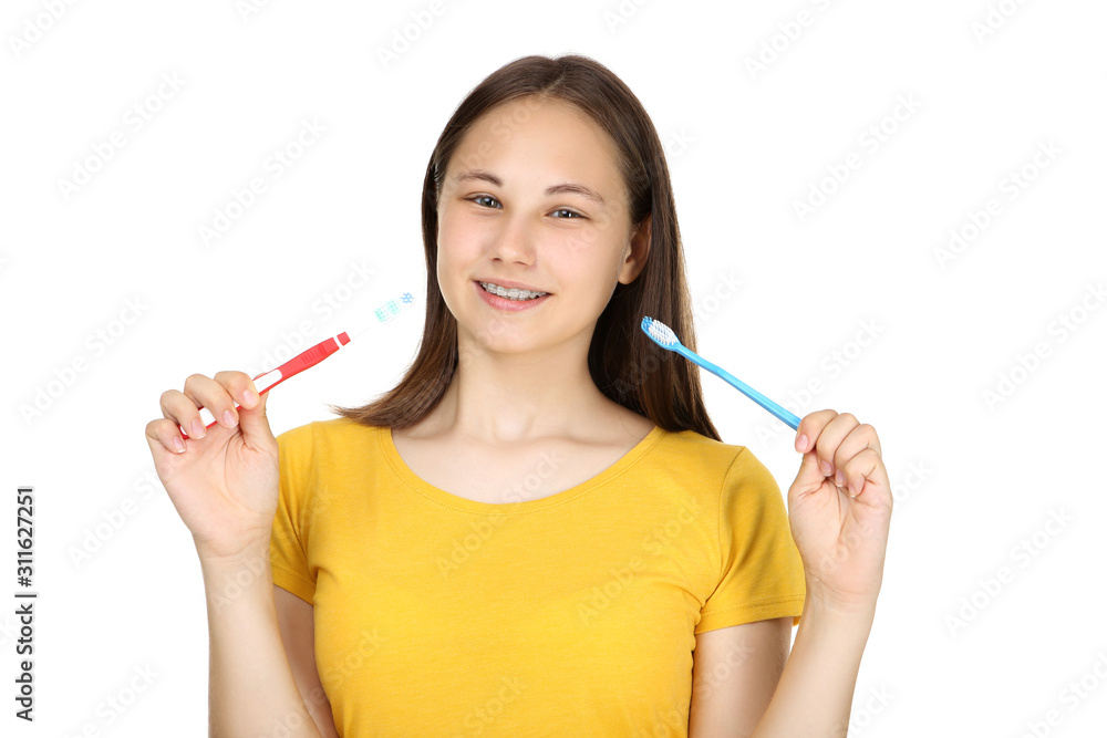 Young girl with dental braces holding toothbrushes on white background Young girl with dental braces holding toothbrushes on white background