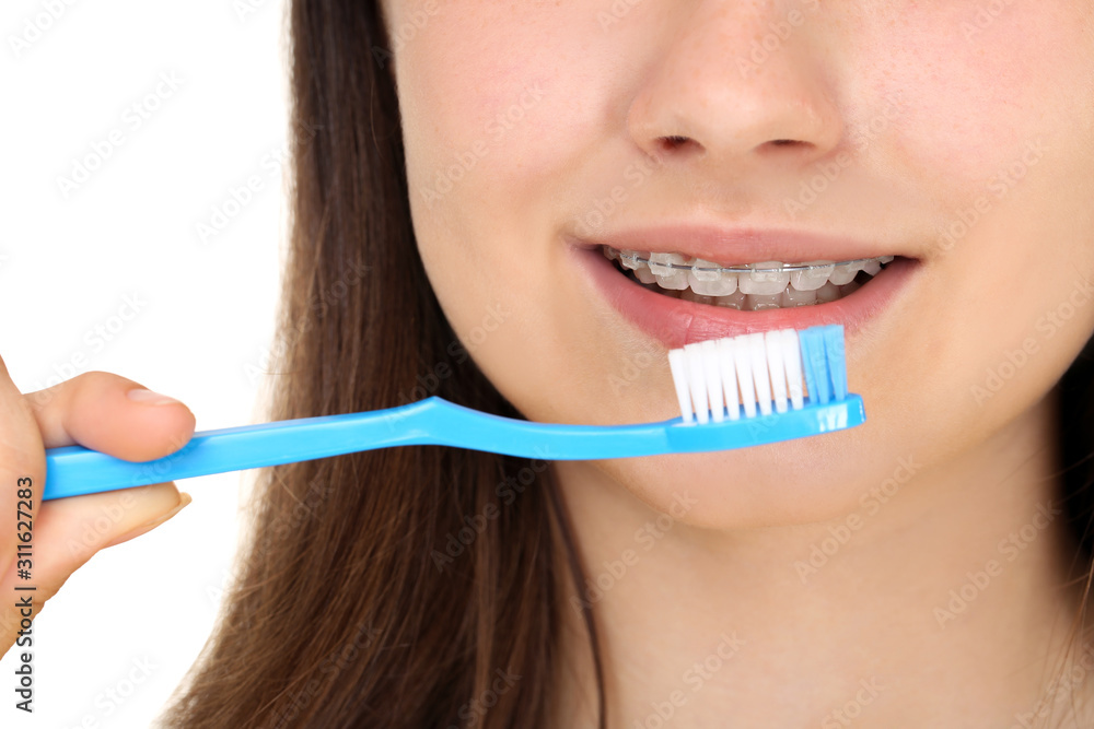 Young girl with dental braces holding toothbrush on white background Young girl with dental braces holding toothbrush on white background