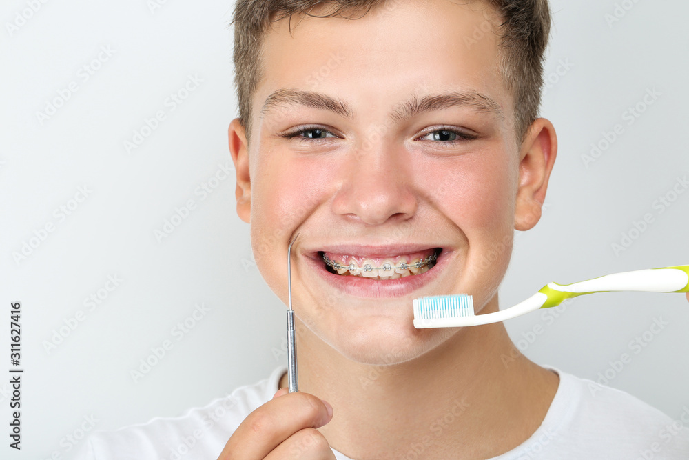 Young man with toothbrush and dentist tool on grey background Young man with toothbrush and dentist tool on grey background