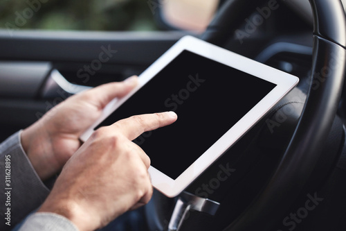 Male hands holding and using tablet computer in car