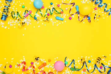 Colorful ribbons with rubber balloons, paper stars and confetti on yellow background