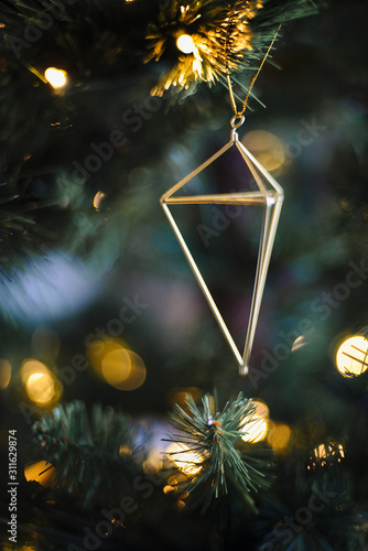 Geometric Christmas ornaments hang from a Christmas tree
