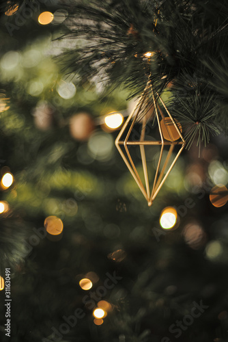 Geometric Christmas ornaments hang from a Christmas tree