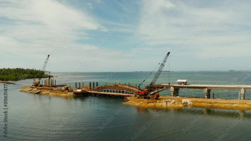 Construction of a bridge across the bay. Construction equipment on the bridge, top view. New bridge on the island of Siargao, Philippines. Construction of a bridge across the bay. Construction equipment on the bridge, top view. New bridge on the island of Siargao, Philippines.