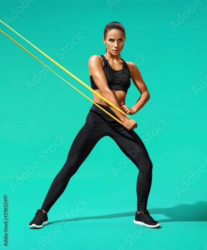 Fotografia Athletic girl performs exercises using resistance band