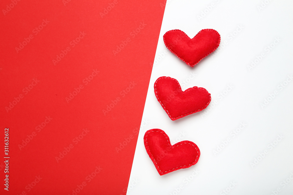 Fototapeta premium Red fabric hearts on colorful paper background