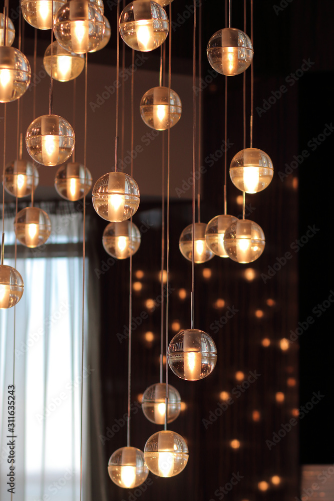 lighting balls on the chandelier in the lamplight, light bulbs hanging from the ceiling, lamps on the dark background, selective focus, vertical lighting balls on the chandelier in the lamplight, light bulbs hanging from the ceiling, lamps on the dark background, selective focus, vertical