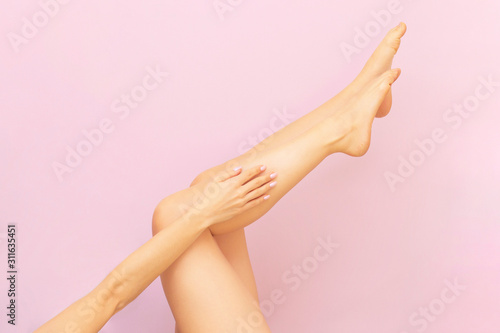 Beautiful long female legs with smooth skin after depilation on a pastel pink background. The concept of clean skin  waxing  shugaring  laser hair removal