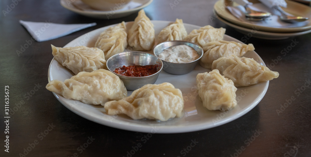 A dish of the tibetan boiled momo with a sauce. Momo is a dish of dough with a filling.