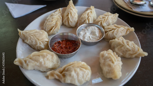 A dish of the tibetan boiled momo with a sauce. Momo is a dish of dough with a filling.