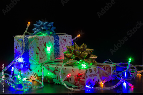 gifts with bows on a dark background entwined with a luminous garland © Jerard