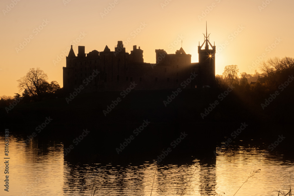 Fototapeta premium Silhouette of an old castle on the lake at sunrise. Rays of the sun break through the window. Linlithgow Palace, Scotland