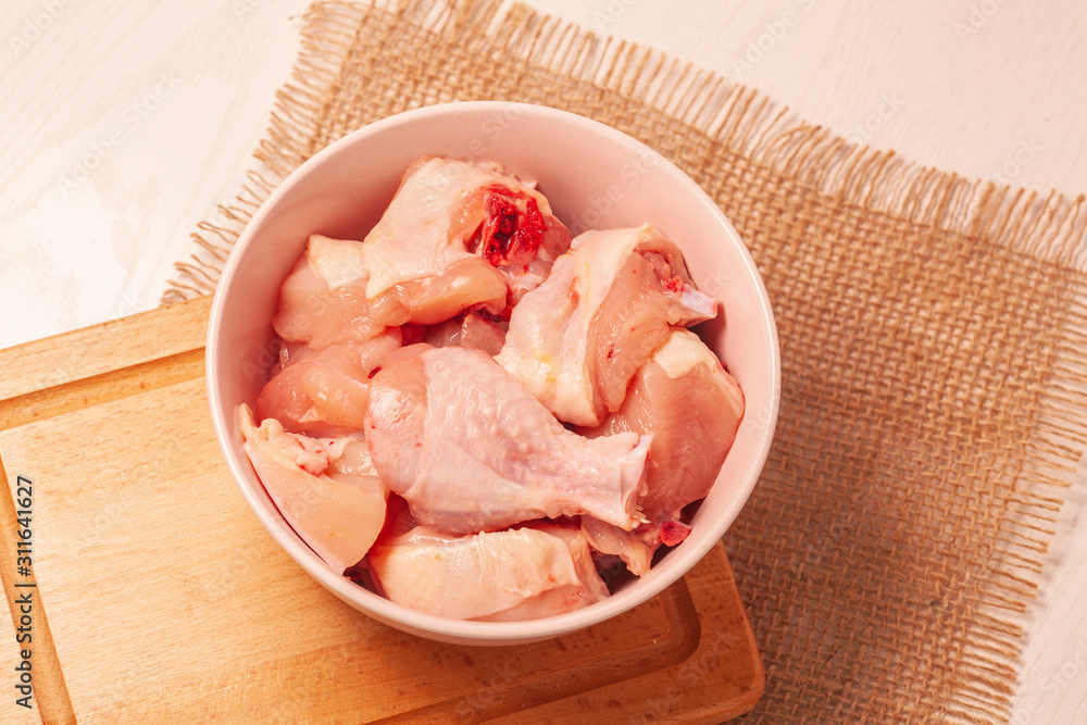 raw chicken in bowl on jute cloth background