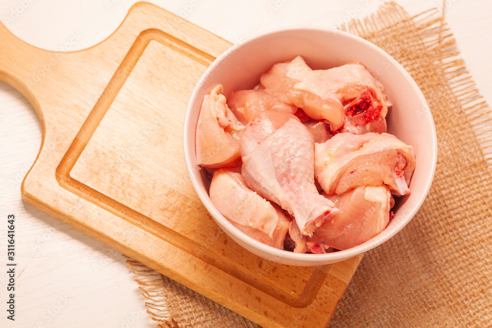 raw chicken in bowl on wooden cutting board background