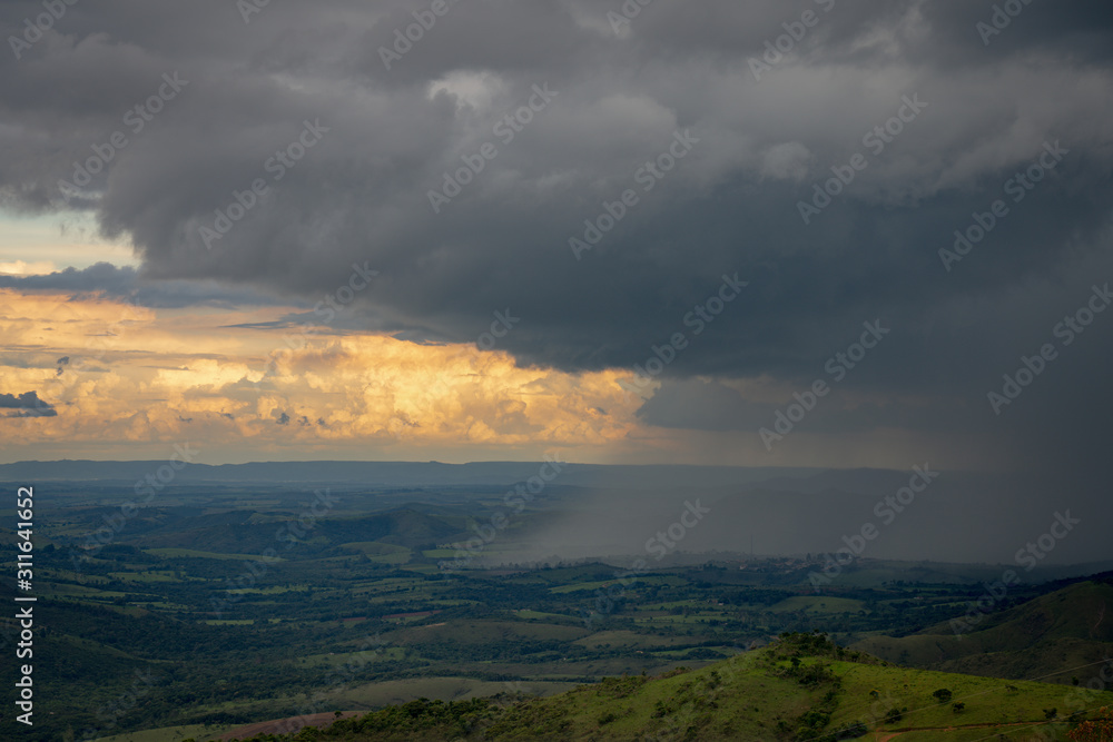 Heavy rain falling into the green fields of Brazil at the sunset
