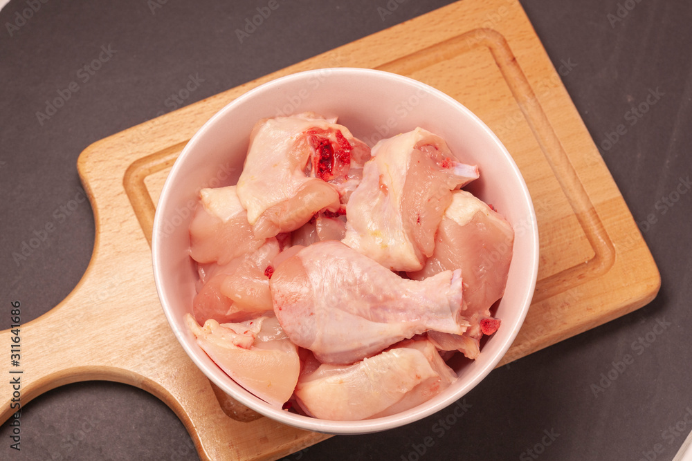 raw chicken in bowl on wooden cutting board background