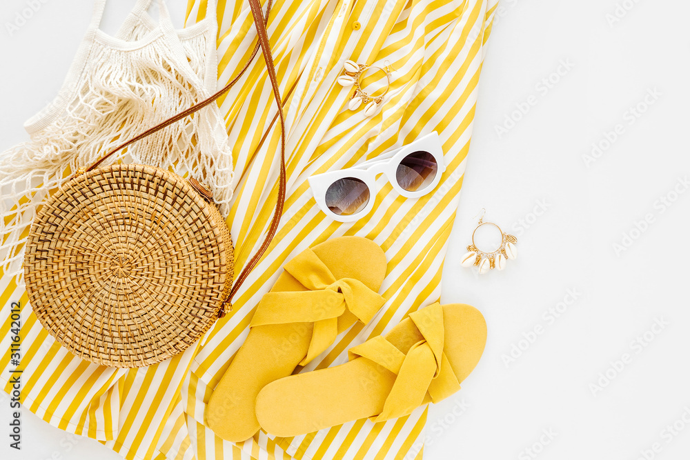 Yellow dress with stripes with slippers, sunglass, and bamboo bag. Women's stylish summer outfit. Trendy clothes. Flat lay, top view. - obrazy, fototapety, plakaty 
