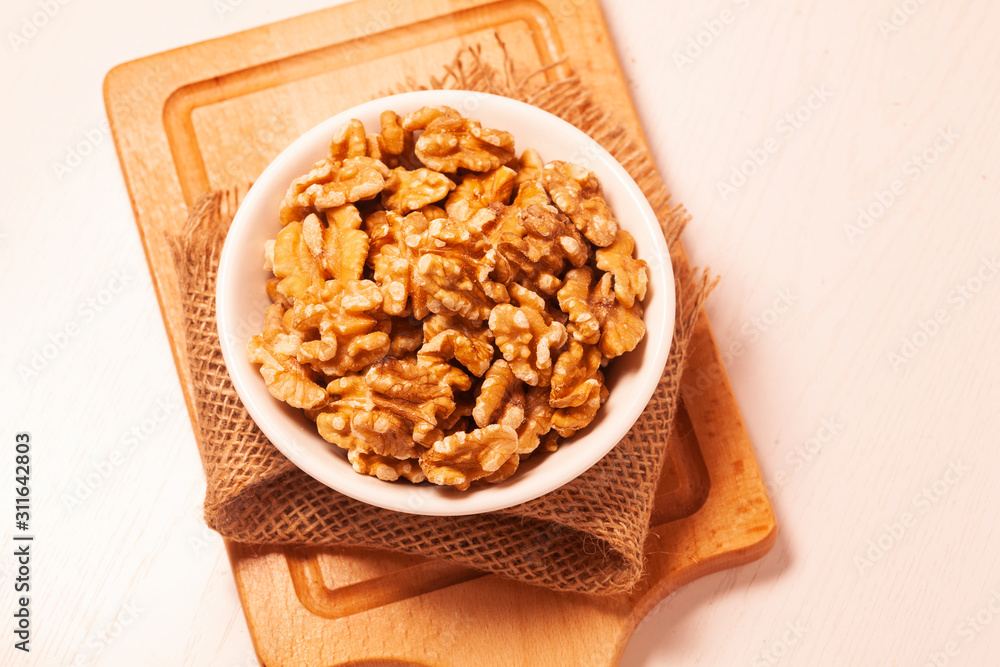 walnuts in bowl with jute cloth and wooden board background walnuts in bowl with jute cloth and wooden board background