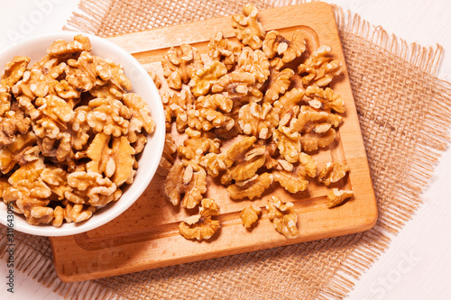 walnuts in bowl with jute cloth and wooden board background 