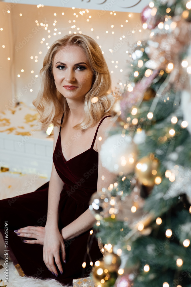 Model posing in studio. Winter holidays concept. Beautiful woman in dress on christmas tree background. Very beautiful girl. Close up portrait of young beautiful happy smiling girl wearing dress. 