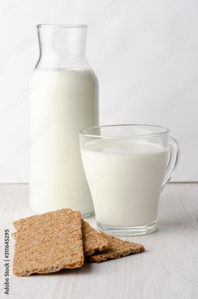 A glass bottle with kefir with bread rolls on the wooden table A glass bottle with kefir with bread rolls on the wooden table