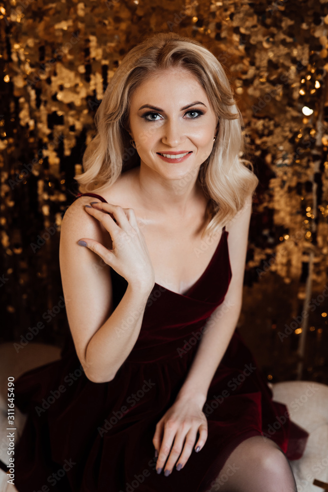 Christmas. Beautiful smiling woman. Makeup. Healthy long hair style. Elegant lady in dress over gold background. Happy new year. Fashion and vogue