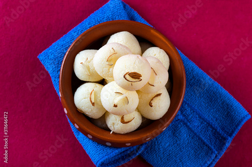 Indian Sweet - Rasgulla, Famous Bengali sweet in clay bowl with napkin on pink background photo