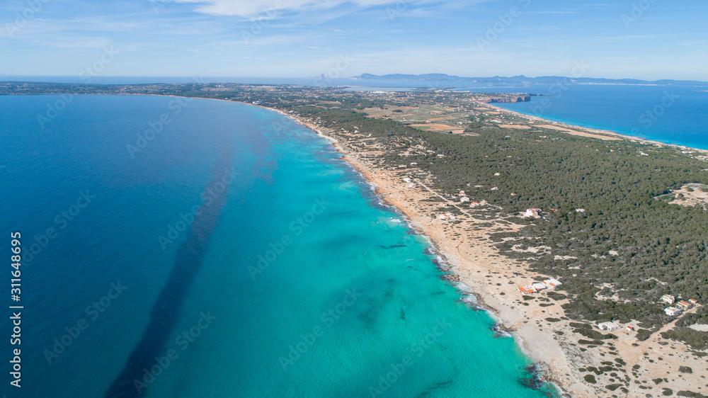 formentera beach seen from drone with turquoise, crystalline sea, trees and Ibiza in the background