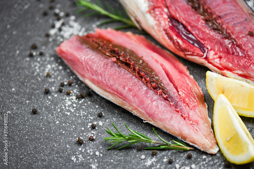 Fresh fish fillet sliced for steak or salad with herbs spices rosemary and lemon - Raw fish seafood on black plate background , Longtail tuna , Eastern little tuna fillet ingredients for cooking food