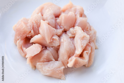 Pieces of raw chicken meat / fresh raw cut chicken fillet on white plate background