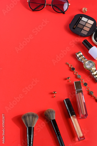 Blogging Beauty Concept. Professional female makeup accessories, watches, bracelet, on a red background. Female background and fashion. Instagram, women's stuff. Flat lay.Vertical frame
