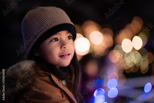 Εκτύπωση καμβά Cute Young Girl in a Hat Gazing at Christmas Lights