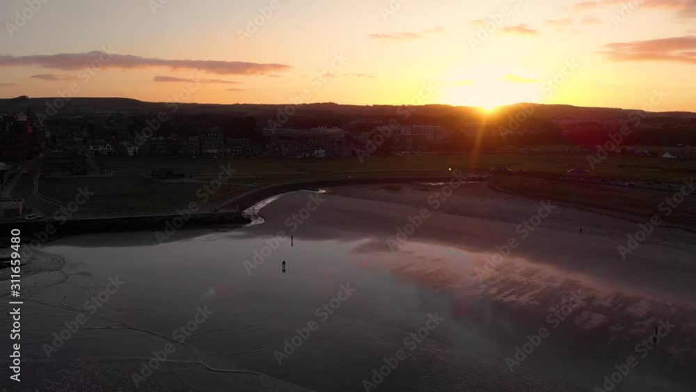 Sunset over beach with colorful reflections across wet sand and clouds in sky. Drone shot mostly static in sky, slight movement. Sunset over beach with colorful reflections across wet sand and clouds in sky. Drone shot mostly static in sky, slight movement.