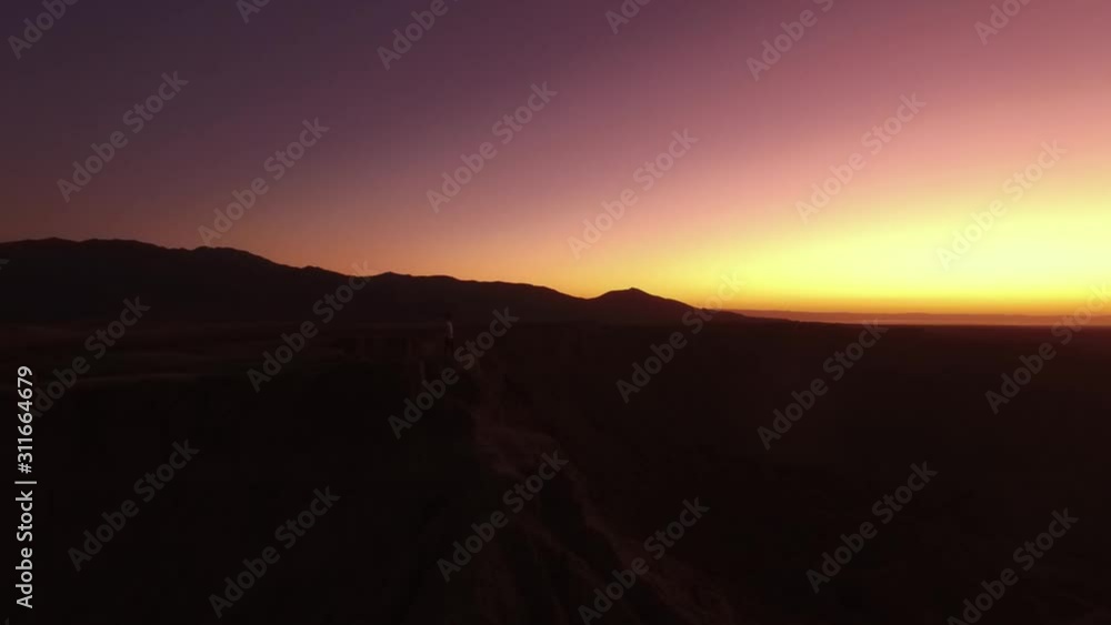 Aerial View California Sunrise Man standing on cliff edge in desert Drone Orbit Aerial View California Sunrise Man standing on cliff edge in desert Drone Orbit