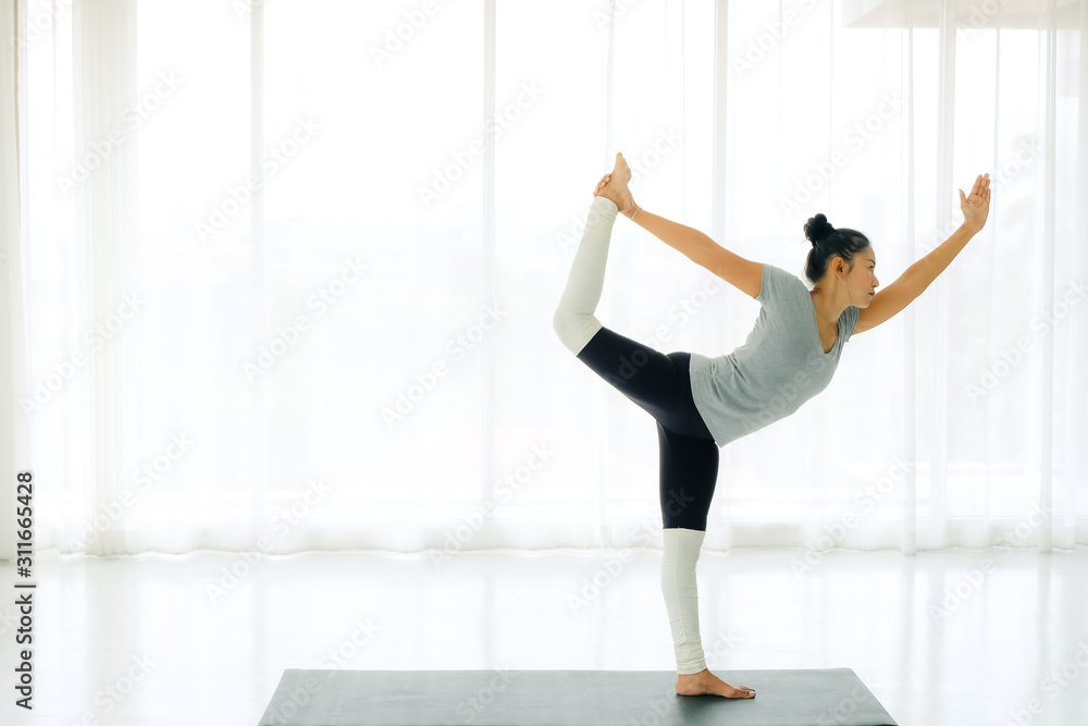 Side view of Beautiful Asian woman practicing yoga, standing in Natarajasana exercise, Lord of the Dance pose, working out, wearing sportswear,full length,indoor,lifestyle healthy concept. Side view of Beautiful Asian woman practicing yoga, standing in Natarajasana exercise, Lord of the Dance pose, working out, wearing sportswear,full length,indoor,lifestyle healthy concept.